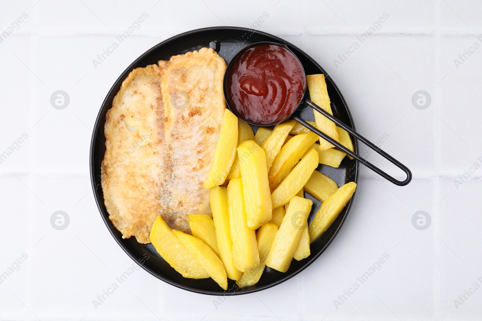 Photo of Delicious fish and chips with ketchup on white tiled table, top view