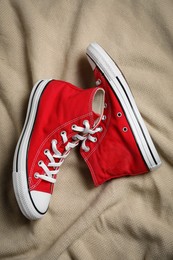 Photo of Pair of new stylish red sneakers on beige cloth, flat lay