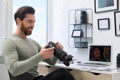 Photo of Professional photographer with digital camera at table in office