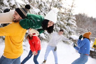 Photo of Group of friends playing snowballs outdoors. Winter vacation