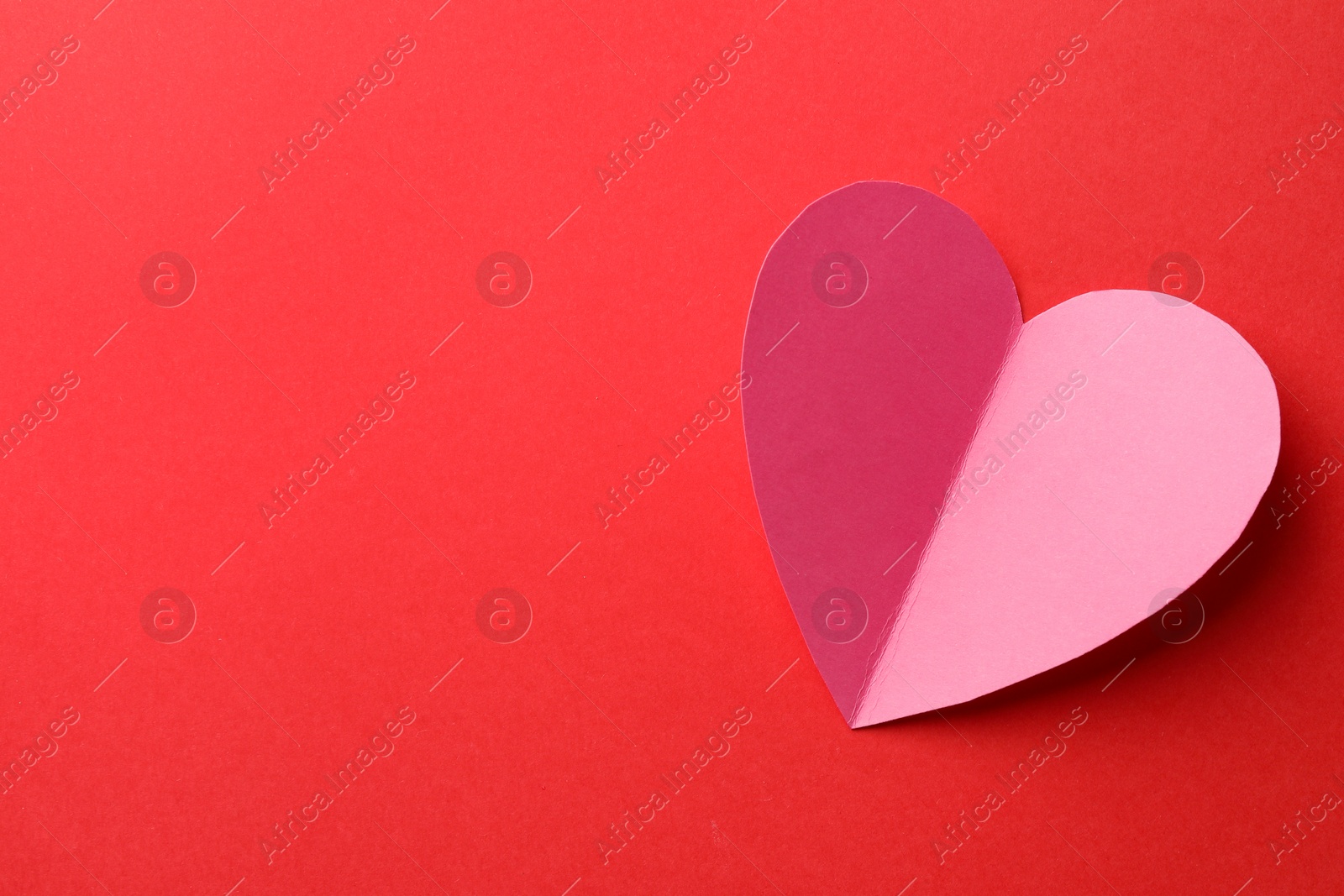 Photo of Pink paper heart on red background, top view. Space for text