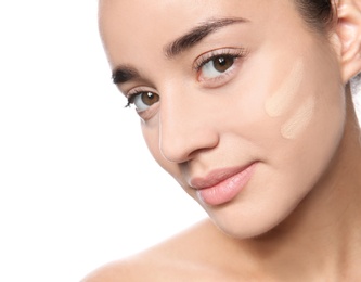 Portrait of young woman with liquid foundation on her face against white background