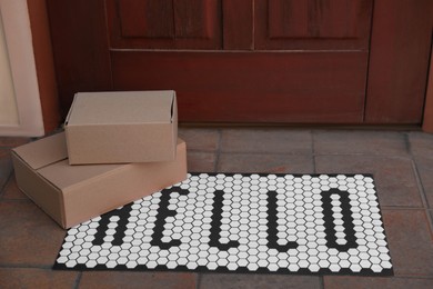 Cardboard boxes on stylish door mat near entrance