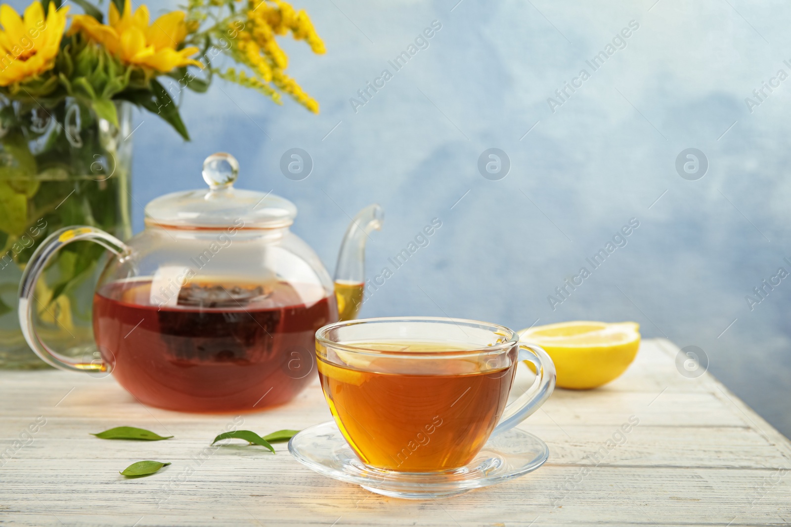 Photo of Glass cup and teapot with black tea on wooden table