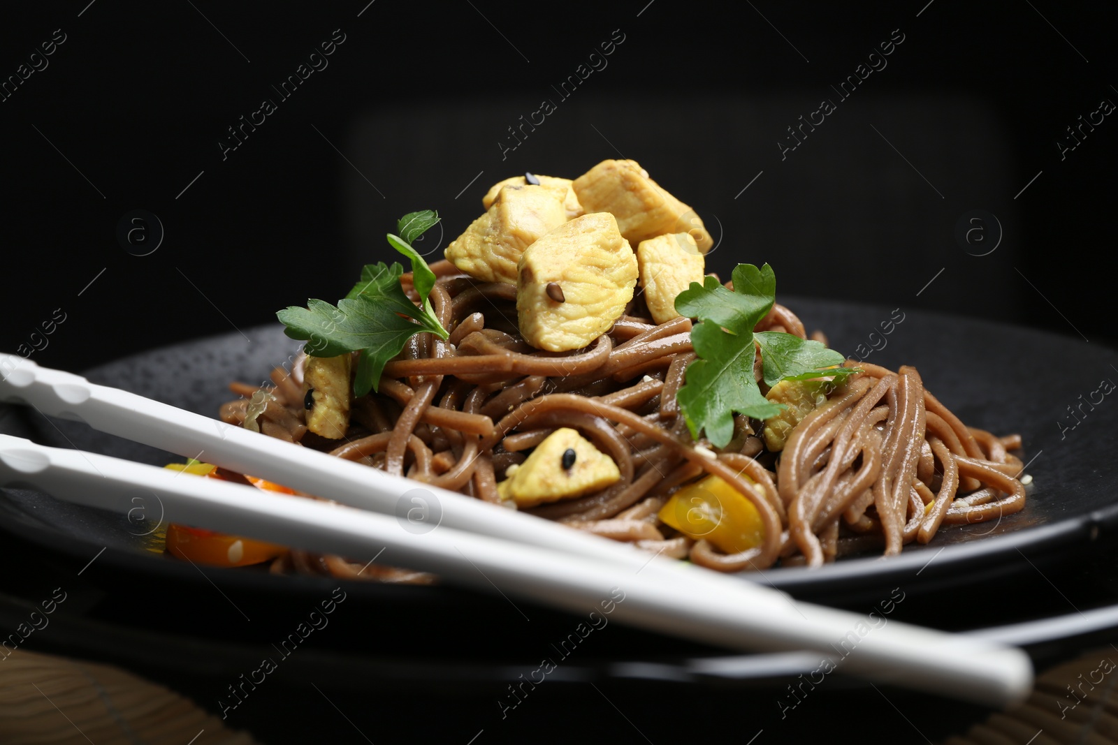 Photo of Stir-fry. Tasty noodles with meat, vegetables and chopsticks on table, closeup