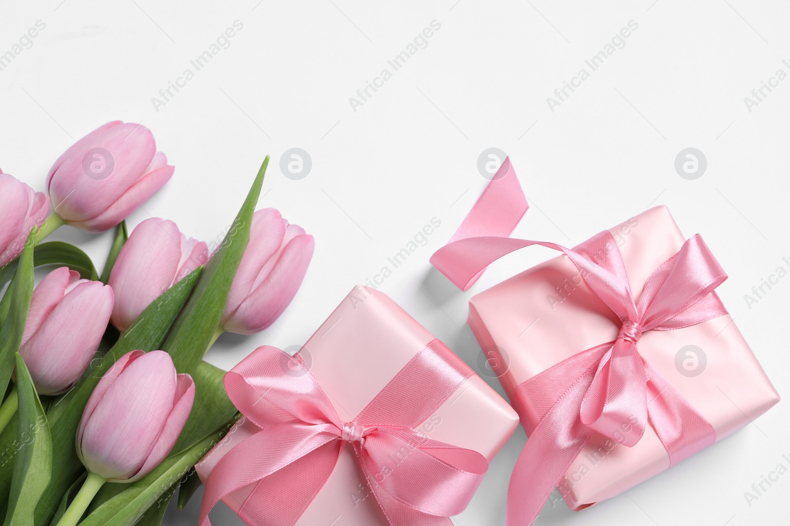 Photo of Beautiful gift boxes and pink tulip flowers on white background, flat lay