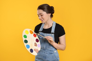 Photo of Woman with painting tools on yellow background. Young artist