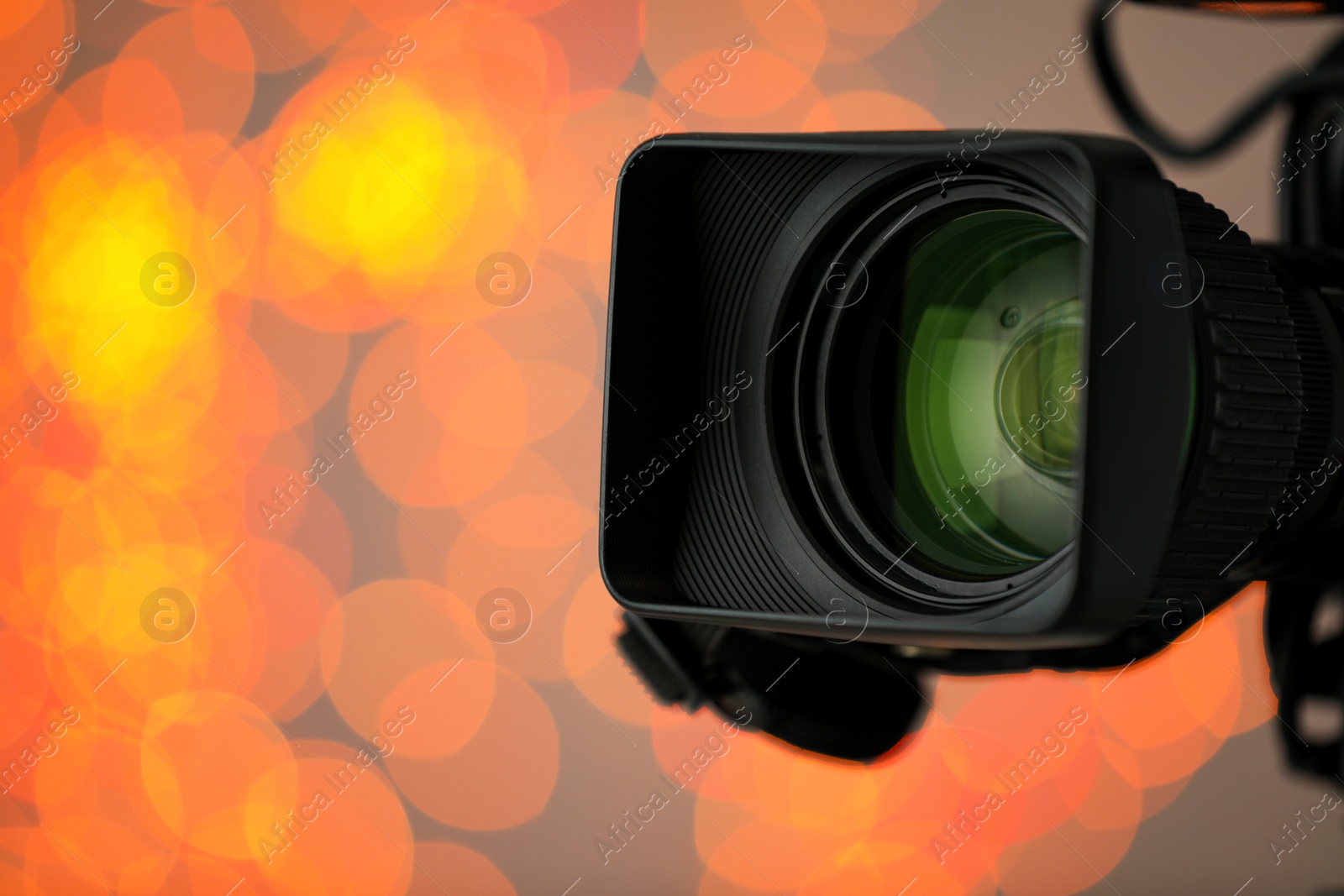 Photo of Modern video camera against blurred lights, closeup