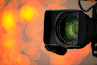 Photo of Modern video camera against blurred lights, closeup