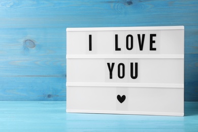 Photo of Lightbox with phrase I Love You on blue wooden table
