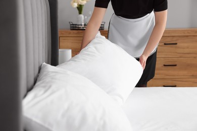 Photo of Chambermaid making bed in hotel room, closeup