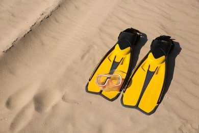 Photo of Pair of flippers and diving mask on sandy beach, space for text