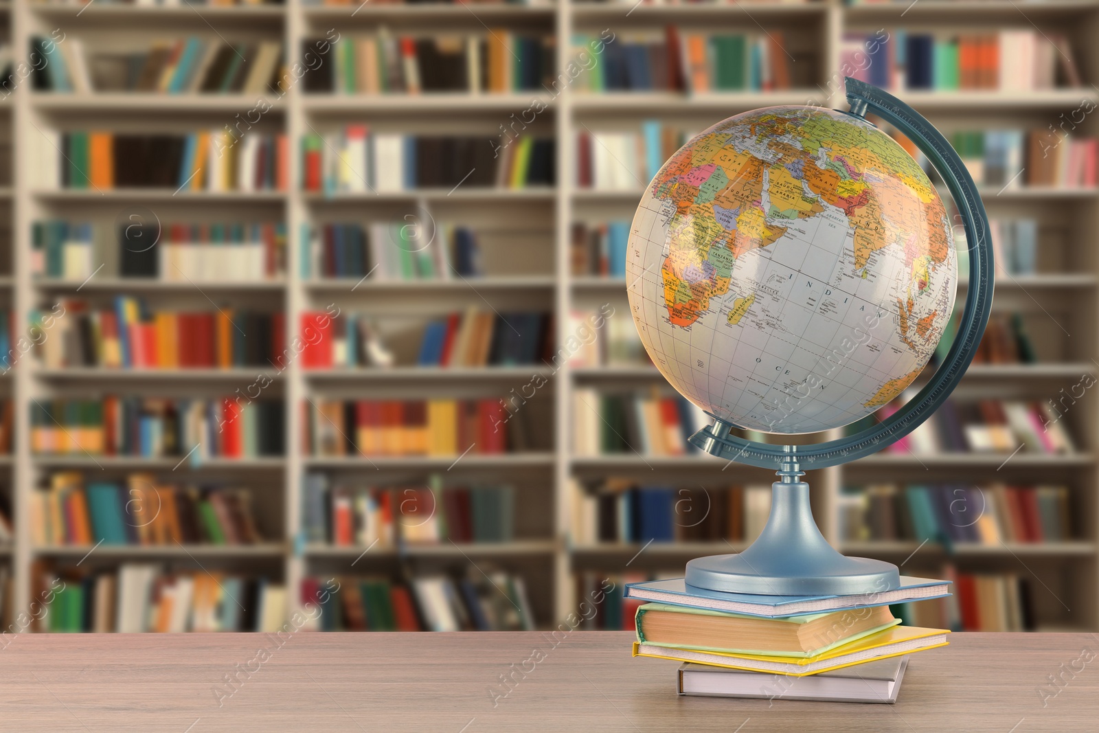 Image of Globe and books on wooden table in library. Space for text