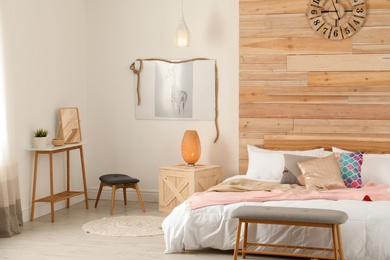 Photo of Stylish room interior with comfortable bed near wooden wall