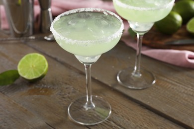 Delicious Margarita cocktail in glasses on wooden table, closeup