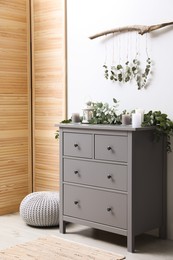 Photo of Stylish room decorated with beautiful eucalyptus garland on chest of drawers