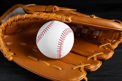 Photo of Catcher's mitt and baseball ball on black background, closeup. Sports game