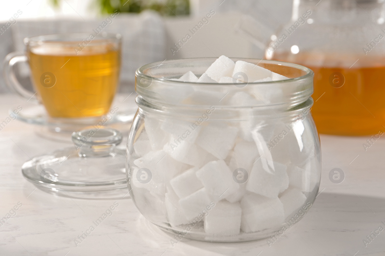 Photo of Jar with refined sugar, honey and cup of tea on white table