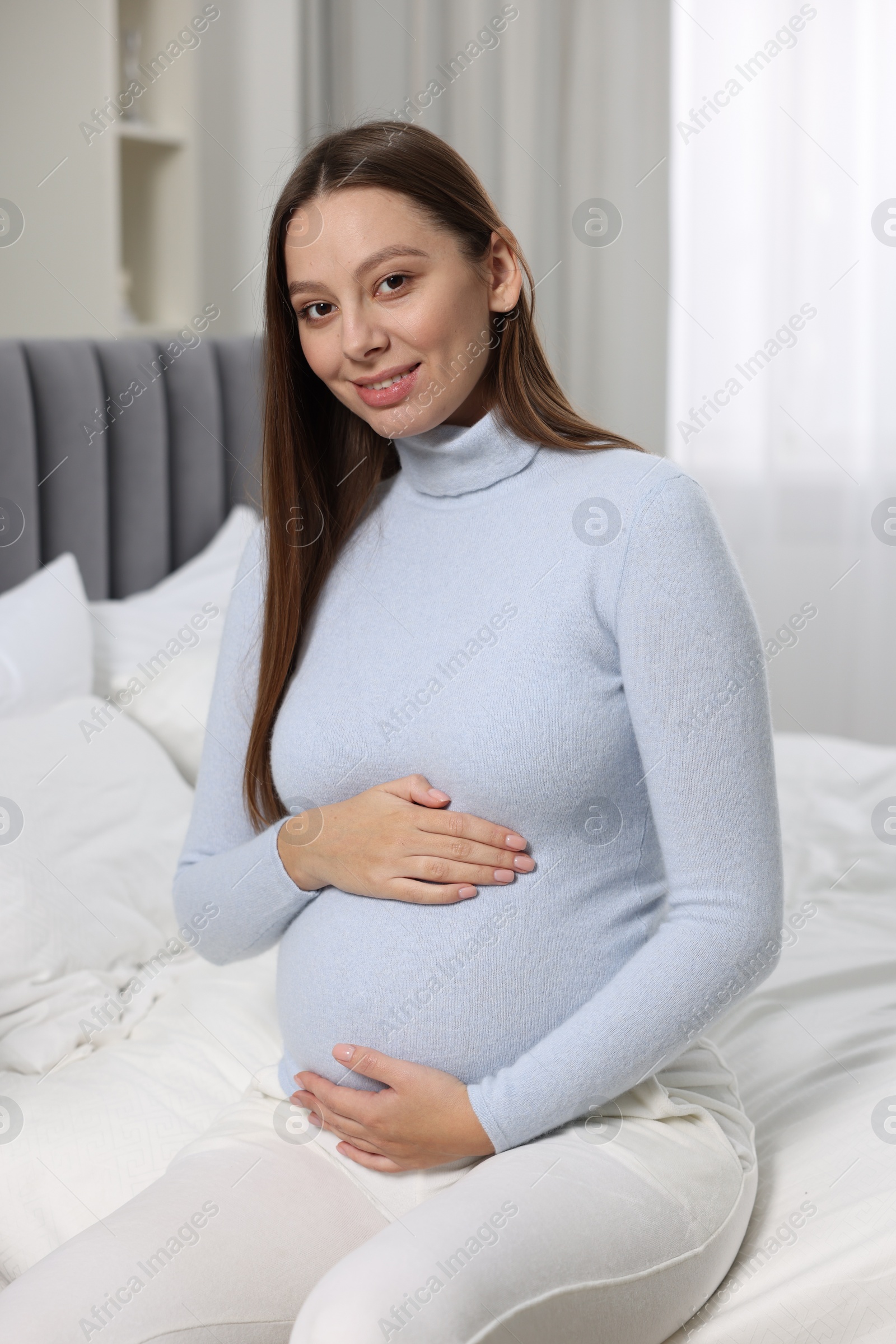 Photo of Beautiful pregnant woman with long hair in bedroom