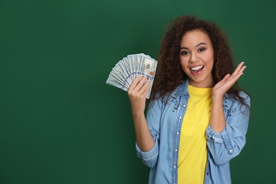 Young African-American woman with money on color background. Space for text