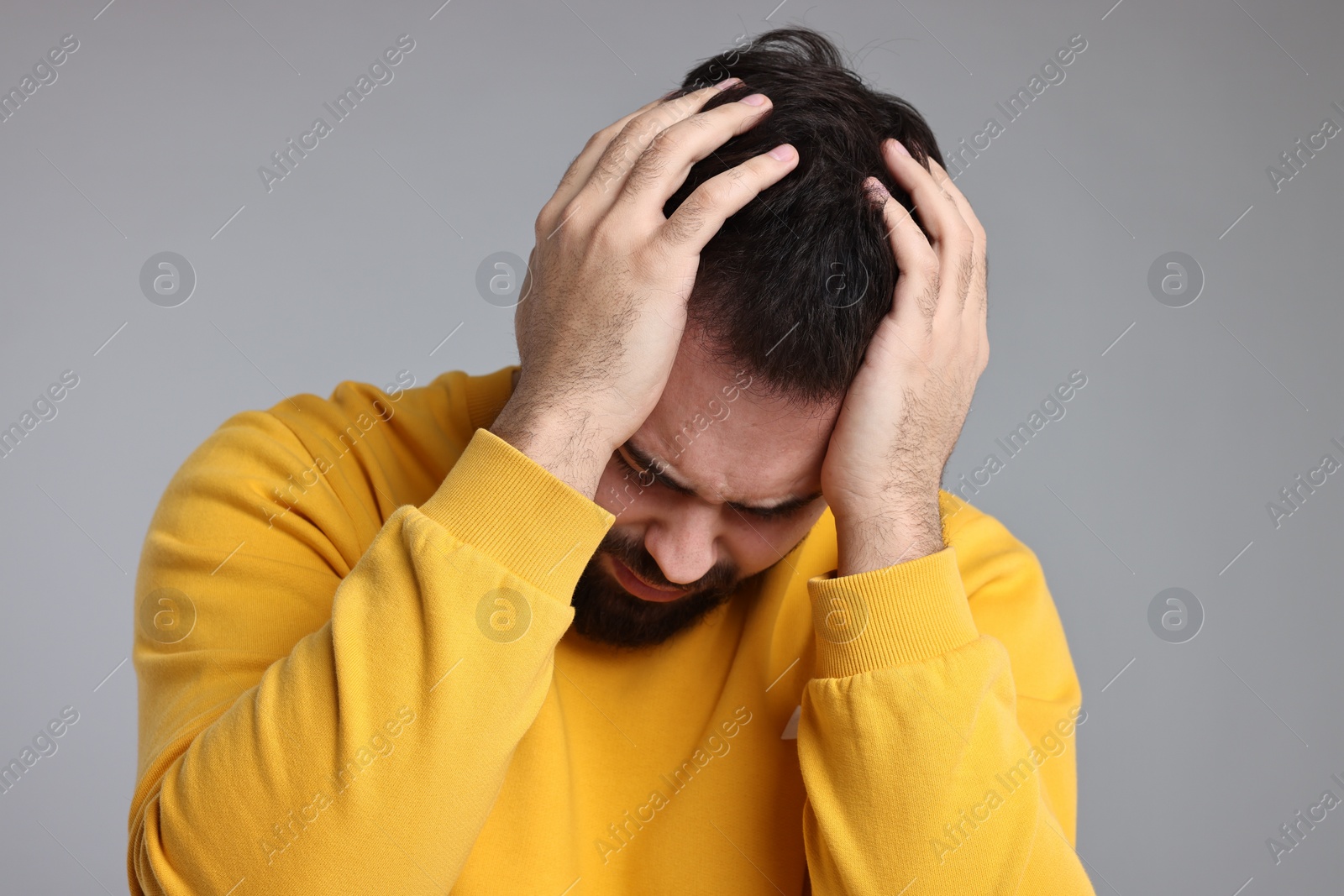 Photo of Sad man grabbing his head on light grey background