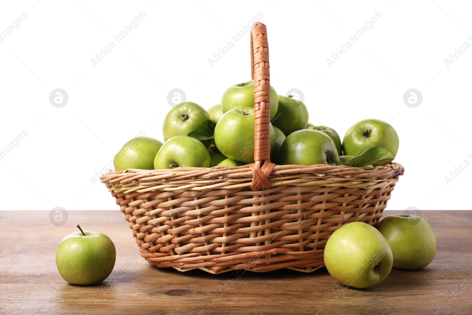 Photo of Ripe green apples in wicker basket on wooden table against white background