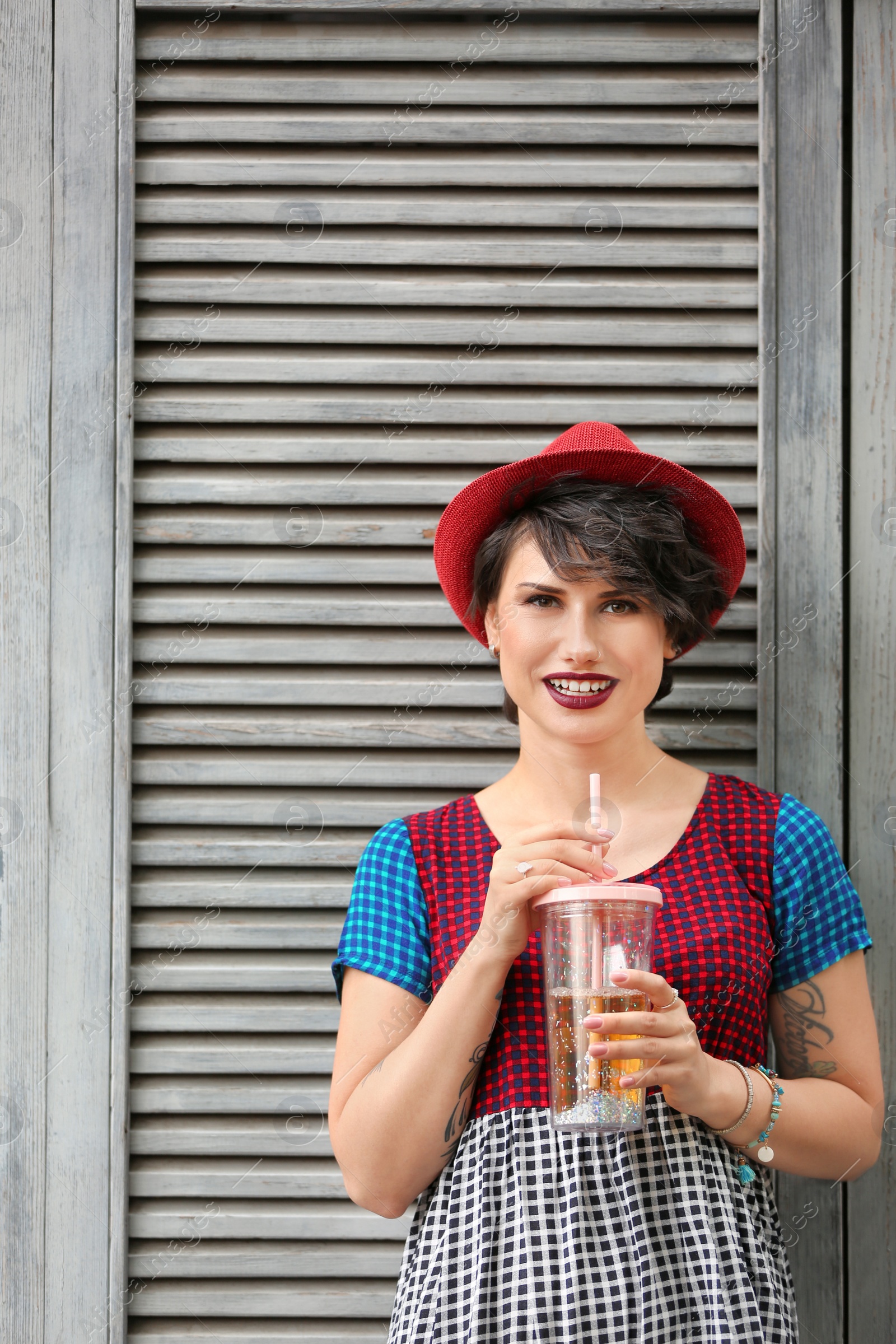 Photo of Young woman with cup of tasty lemonade near wooden wall