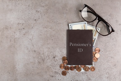 Photo of Pension certificate with American money and glasses on grey stone table, flat lay. Space for text