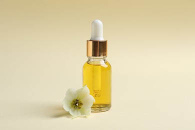 Photo of Bottle with cosmetic oil and flower on beige background