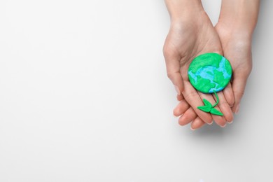 Photo of Woman holding model of planet with green seedling and space for text on white background, top view. Earth Day
