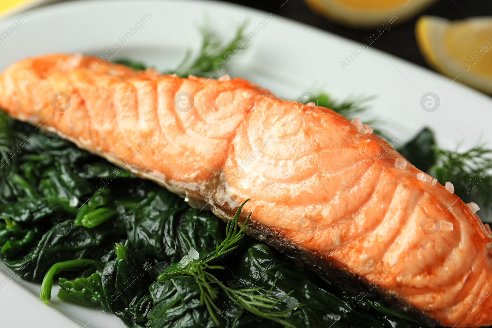 Photo of Tasty salmon with spinach on plate, closeup