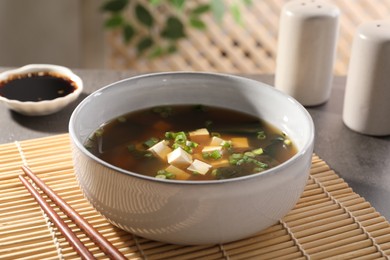 Bowl of delicious miso soup with tofu and chopsticks on table, closeup