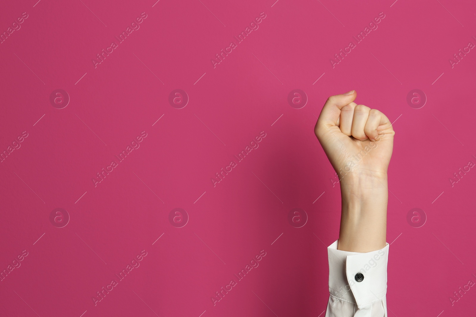 Photo of Young woman showing clenched fist on color background. Space for text