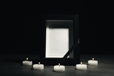 Funeral photo frame and burning candles on dark background