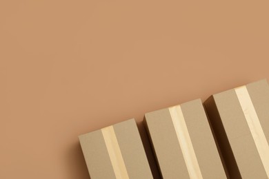 Cardboard boxes on light brown background, flat lay. Space for text