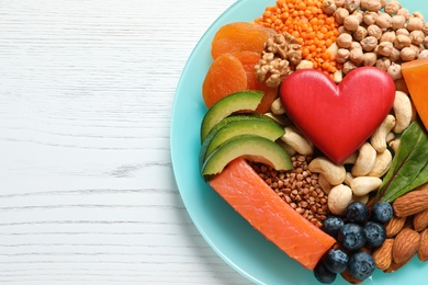 Photo of Plate with heart-healthy products on wooden background, top view. Space for text