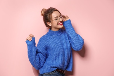 Beautiful young woman in warm sweater on color background