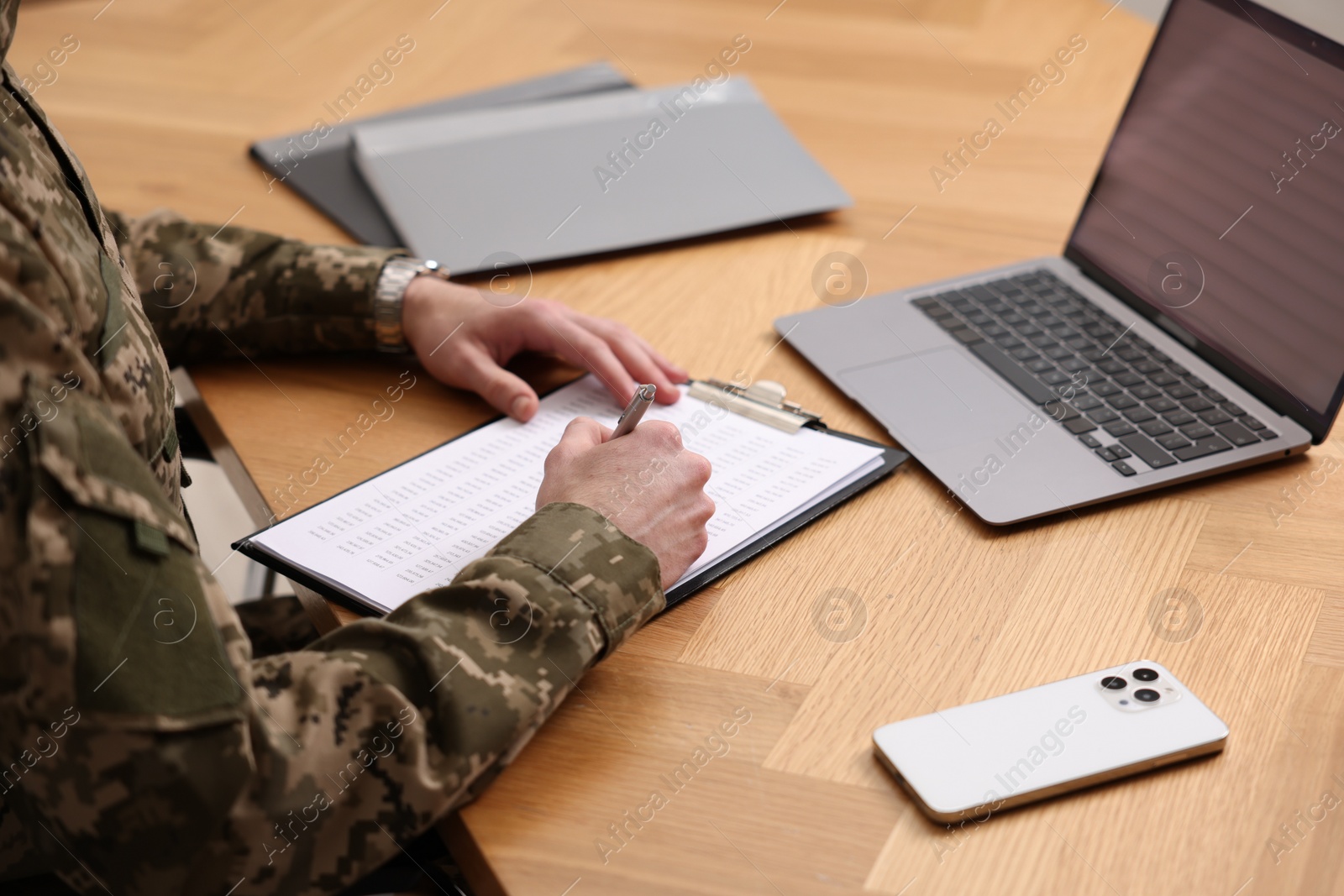 Photo of Military service. Soldier working at wooden table, closeup