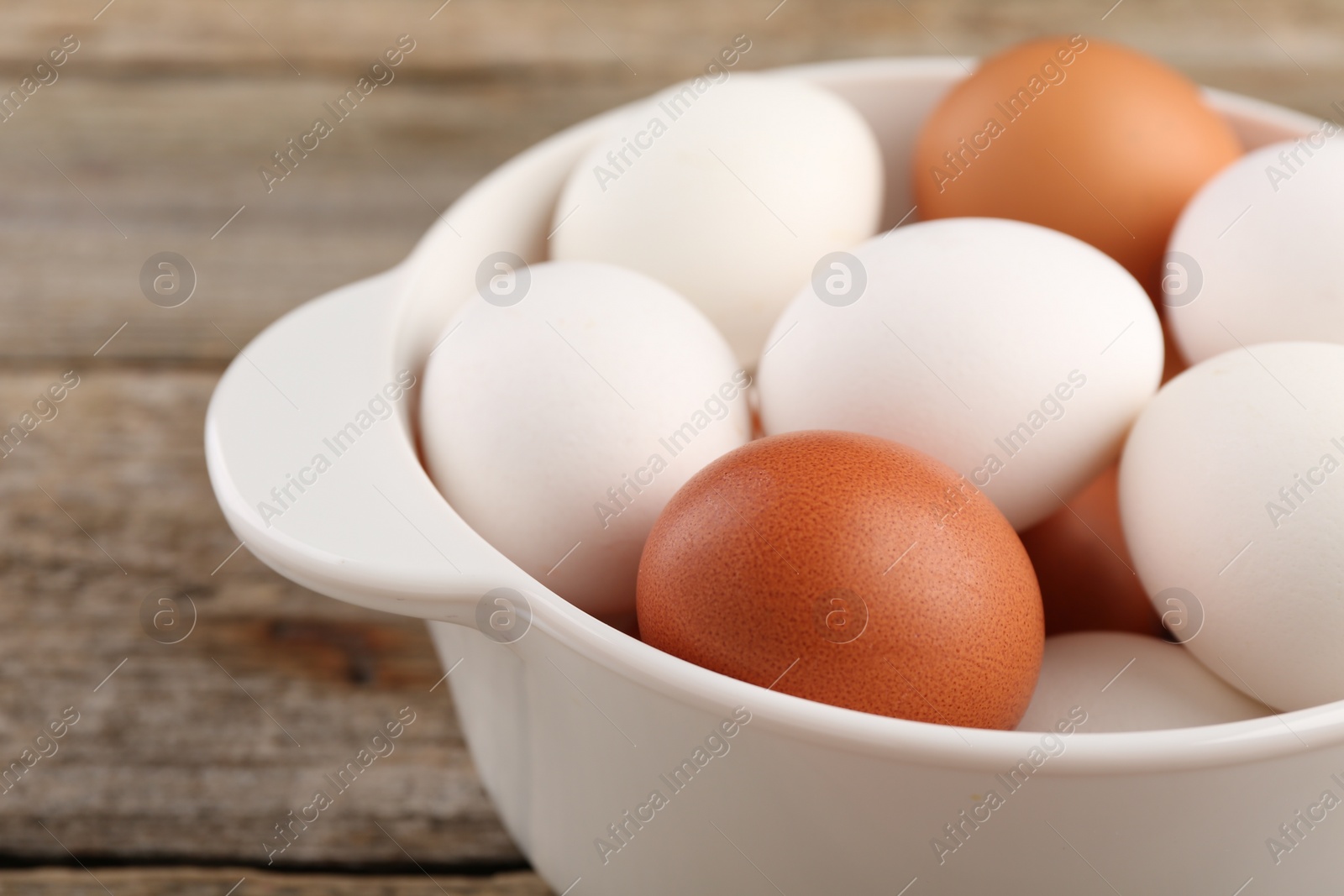 Photo of Unpeeled boiled eggs in saucepan on old wooden table, closeup