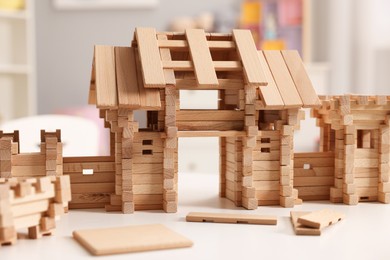 Photo of Wooden entry gate and building blocks on white table indoors, closeup. Children's toy