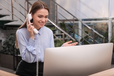 Photo of Female receptionist talking on phone at workplace