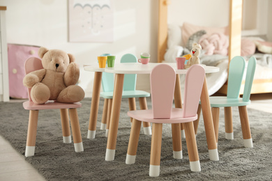 Photo of Small table and chairs with bunny ears in children's bedroom interior