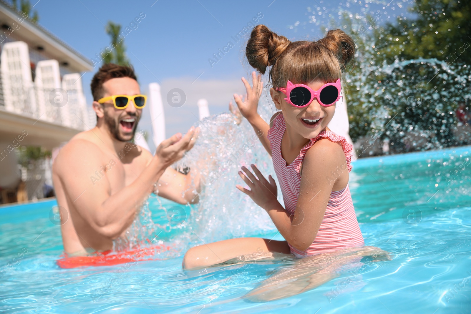 Photo of Father and daughter having fun in swimming pool. Family vacation