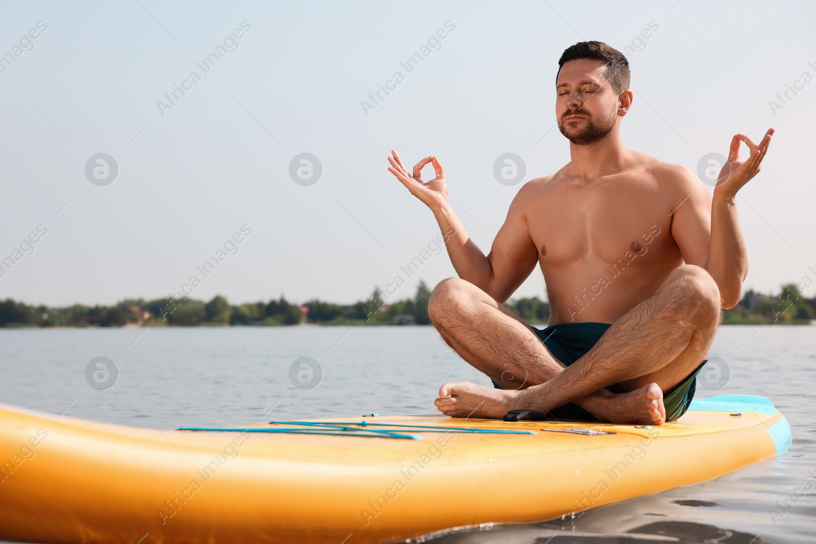 Photo of Man practicing yoga on SUP board on river