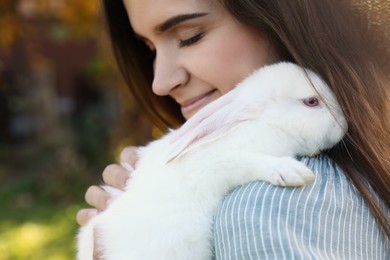 Photo of Happy woman with cute rabbit outdoors on sunny day, closeup