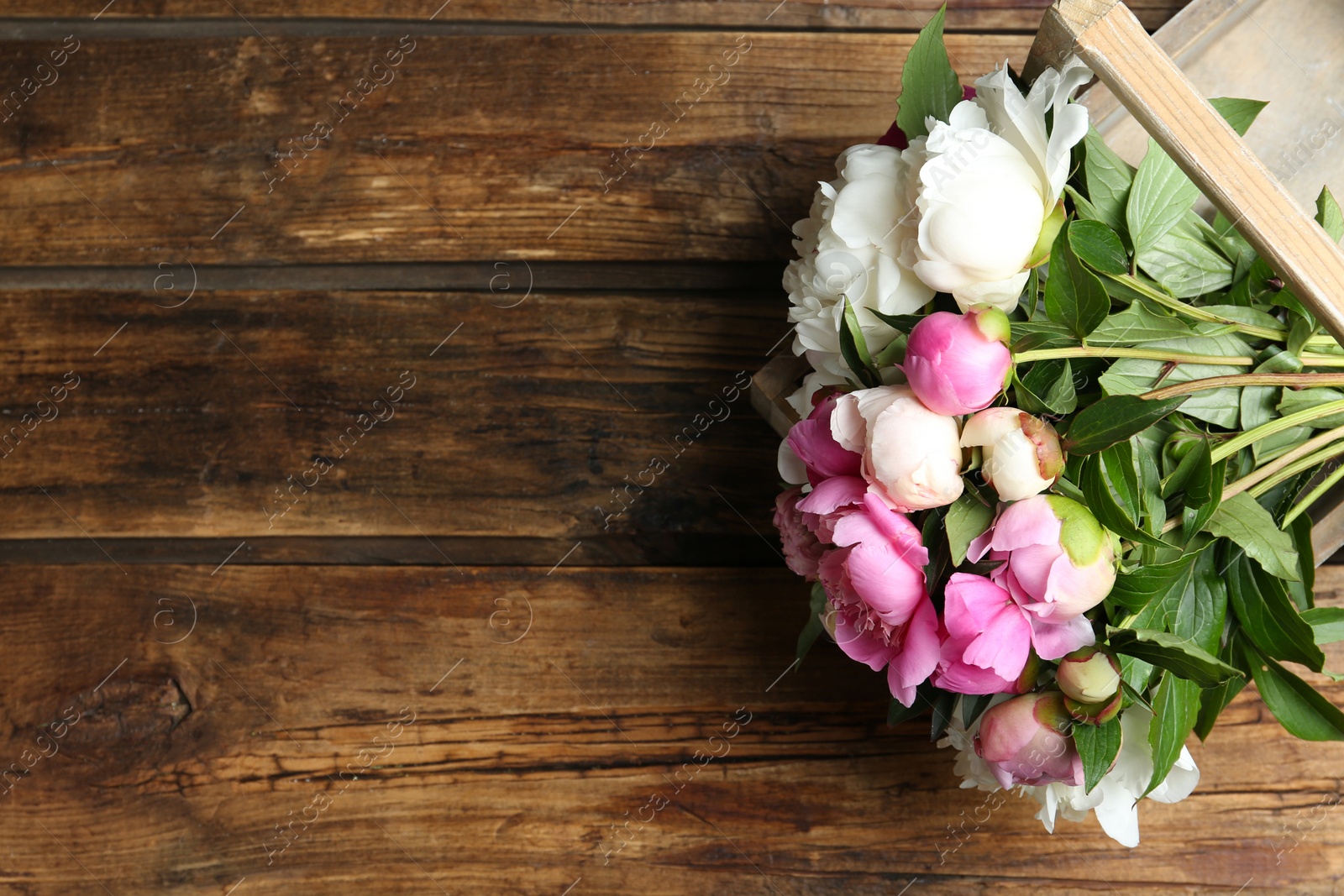 Photo of Bouquet of beautiful peonies on wooden table, top view. Space for text