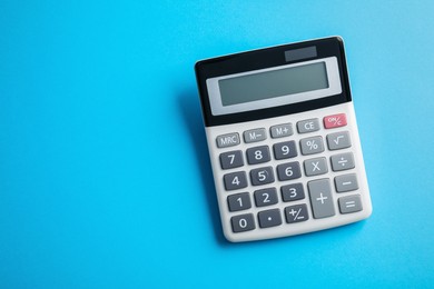 Calculator on light blue background, top view. Space for text