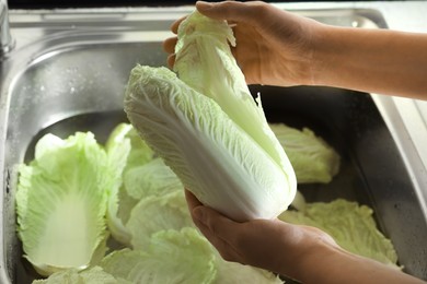 Woman washing fresh Chinese cabbages in sink, closeup