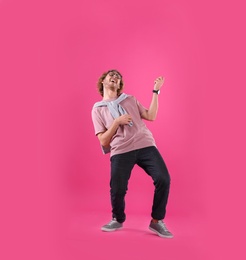 Young man playing air guitar on color background