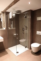 Photo of Stylish bathroom with toilet bowl and shower stall in luxury hotel. Interior design